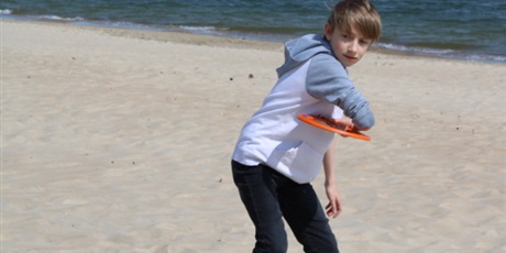 Powiększ grafikę: Chłopiec na plaży, trzymający frisbee